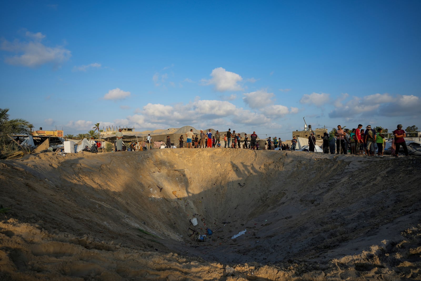 FILE - Palestinians look at the destruction after an Israeli airstrike on a crowded tent camp housing Palestinians displaced by the war in Muwasi, Gaza Strip, on Sept. 10, 2024. (AP Photo/Abdel Kareem Hana, File)