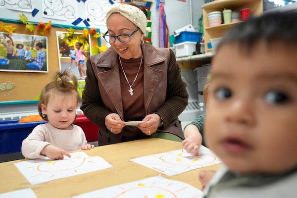 Volunteer Victoria Vasquez, 70, of Providence, R.I., center, supervises one-and-a-half year olds Scarlett Thomas, left, and Liam Echevarria Gaytan, right, in an early childcare program at Federal Hill House, Tuesday, Nov. 12, 2024, in Providence, R.I. (AP Photo/Steven Senne)