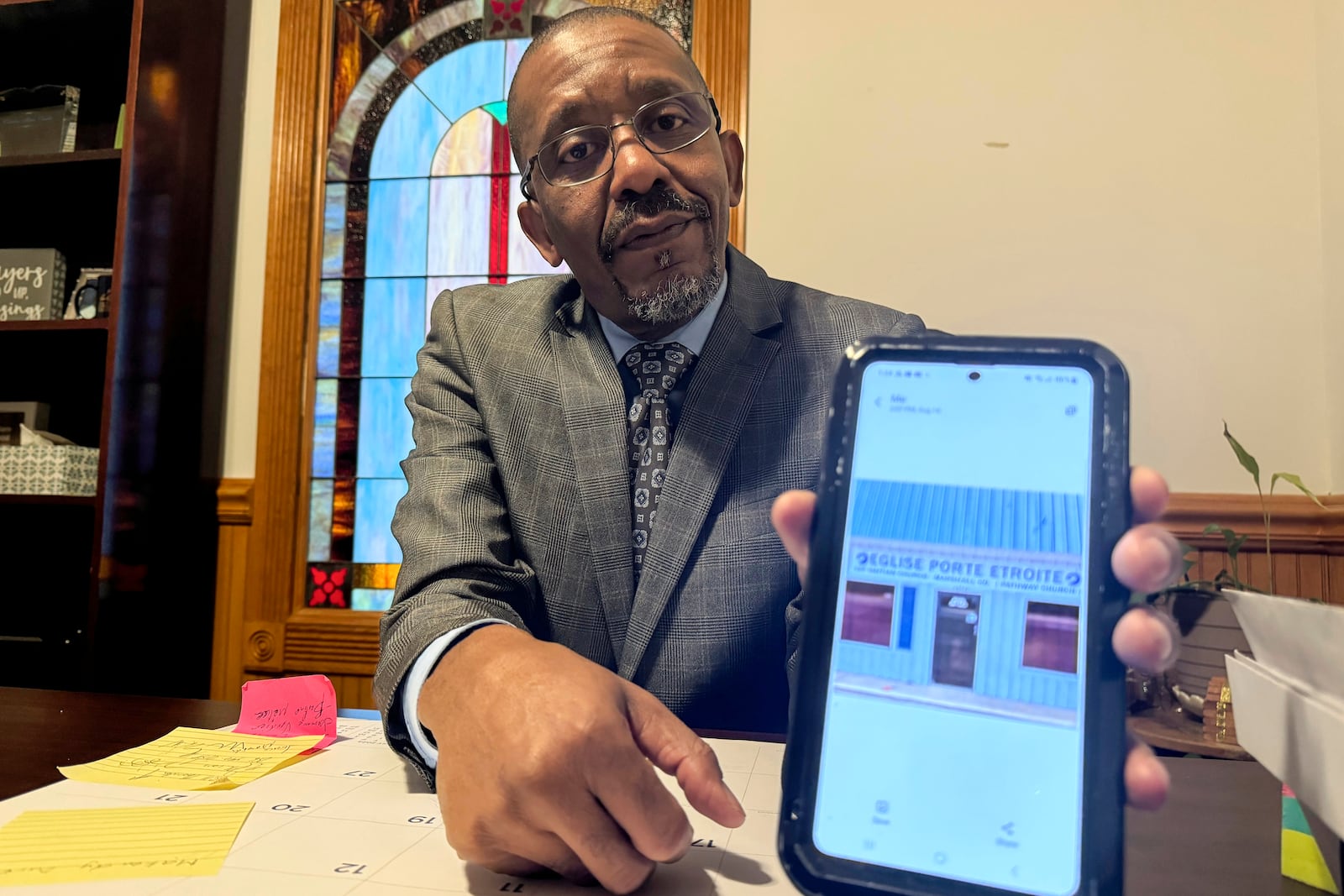 Pastor John Pierre-Charles shows a picture of the original building where the Eglise Porte Etroite church met when he first started it in 2010, in Albertville, Ala., on Sept. 29, 2024. (AP Photo/Safiyah Riddle)