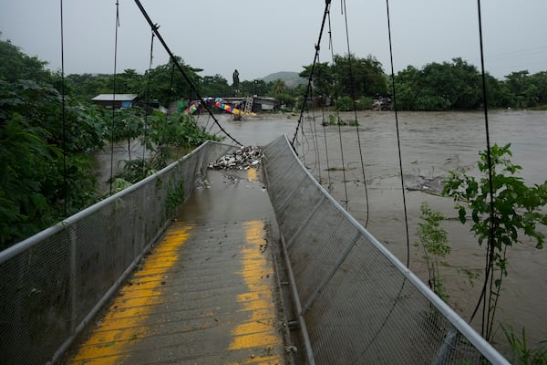 A pedestrian bridge collapsed due to flooding caused by rains brought on by Tropical Storm Sara in San Pedro Sula, Honduras Saturday, Nov. 16, 2024. (AP Photo/Moises Castillo)