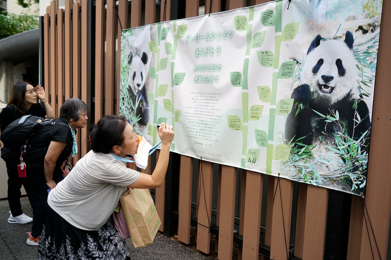 Visitors take a look at a banner saying " Thank you Ri Ri and Shin Shin, with 5,000 days of gratitude" after they saw the giant pandas Ri Ri and Shin Shin at Ueno Zoo, a day before their return to China, Saturday, Sept. 28, 2024, in Tokyo. (AP Photo/Eugene Hoshiko)