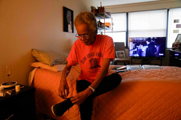 Bernadine Gibson, 82, puts on shoes as she prepares to see renovations being done to the building her family has lived in for 27 years, Monday, Nov. 18, 2024, in Chicago. (AP Photo/Erin Hooley)