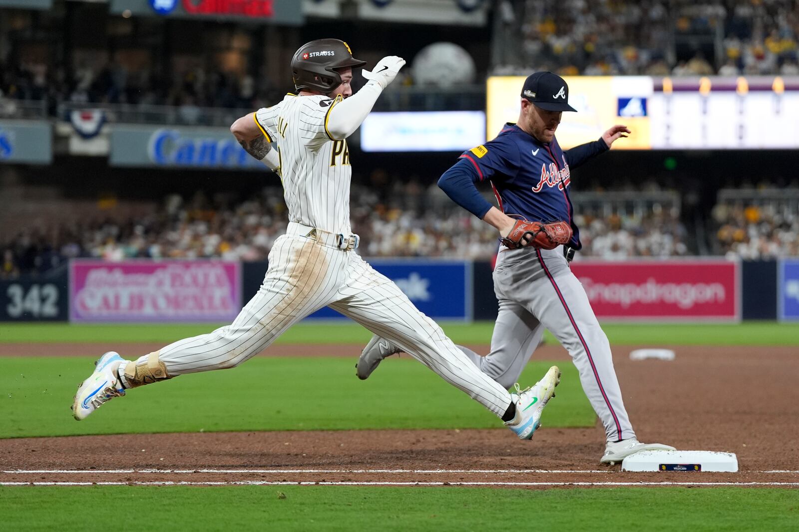 San Diego Padres' Jackson Merrill, left, is out at first base on a ground ball behind Atlanta Braves relief pitcher Aaron Bummer during the fourth inning in Game 1 of an NL Wild Card Series baseball game Tuesday, Oct. 1, 2024, in San Diego. (AP Photo/Gregory Bull)