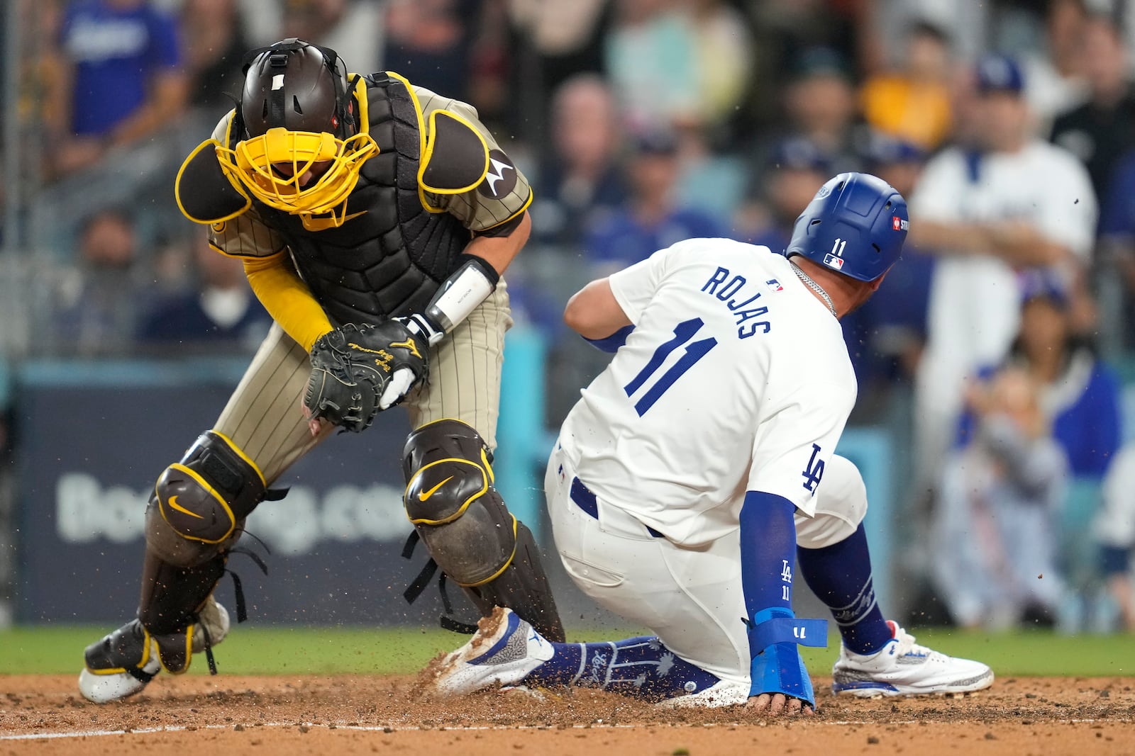 Los Angeles Dodgers' Miguel Rojas (11) is forced out at home plate by San Diego Padres catcher Kyle Higashioka, left, after a ground ball by Freddie Freeman during the fourth inning in Game 1 of baseball's NL Division Series, Saturday, Oct. 5, 2024, in Los Angeles. (AP Photo/Ashley Landis)